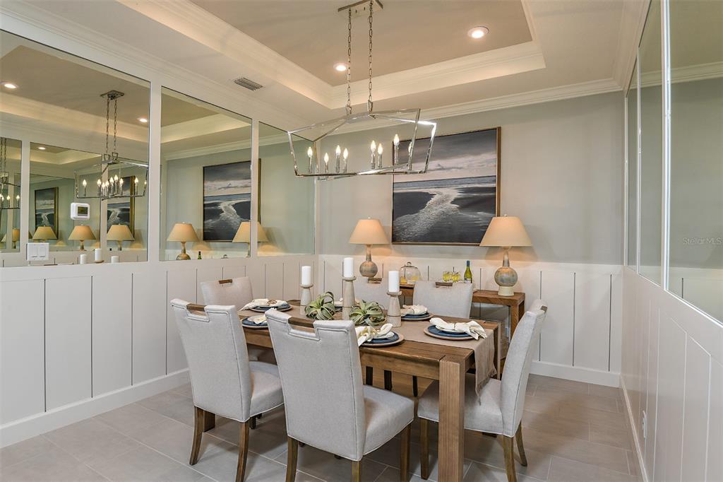 A dining room features a wooden table, upholstered chairs, a chandelier, and mirrored wall panels — 13304 SANTINI CIRCLE, ENGLEWOOD, FL