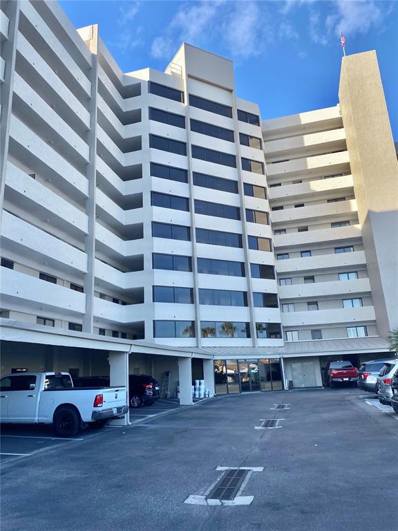 A multi-story apartment building features a covered parking area and a paved lot — 6035 SEA RANCH DRIVE UNIT 215, HUDSON, FL