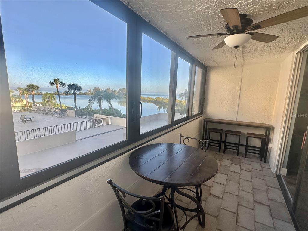A sunroom features a round table, a bar-height table with stools, and a water view — 6035 SEA RANCH DRIVE UNIT 215, HUDSON, FL