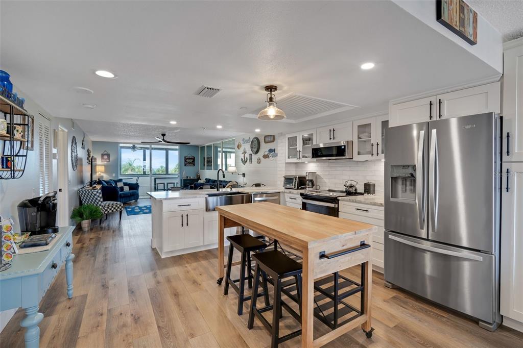 A kitchen with a wooden island, white cabinetry, stainless steel appliances, and wood-look flooring — 6035 SEA RANCH DRIVE UNIT 215, HUDSON, FL