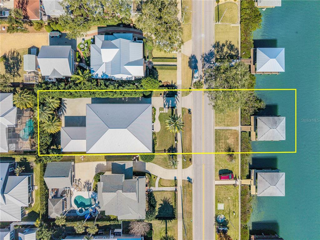 An aerial view shows a waterfront house with a metal roof and a private dock — 1212 S RIVERSIDE DRIVE, NEW SMYRNA BEACH, FL
