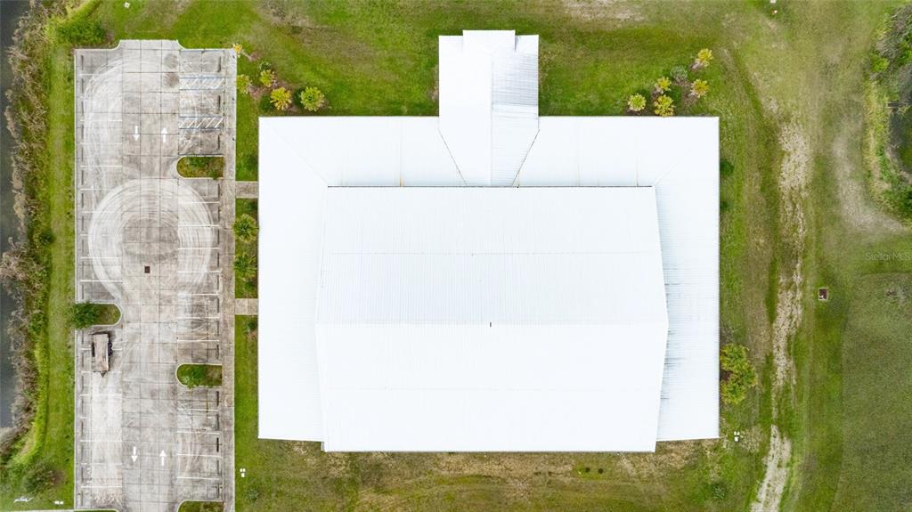 An aerial view shows a building with a white metal roof next to a parking lot — 4015 S WILLIAMSON BOULEVARD, PORT ORANGE, FL