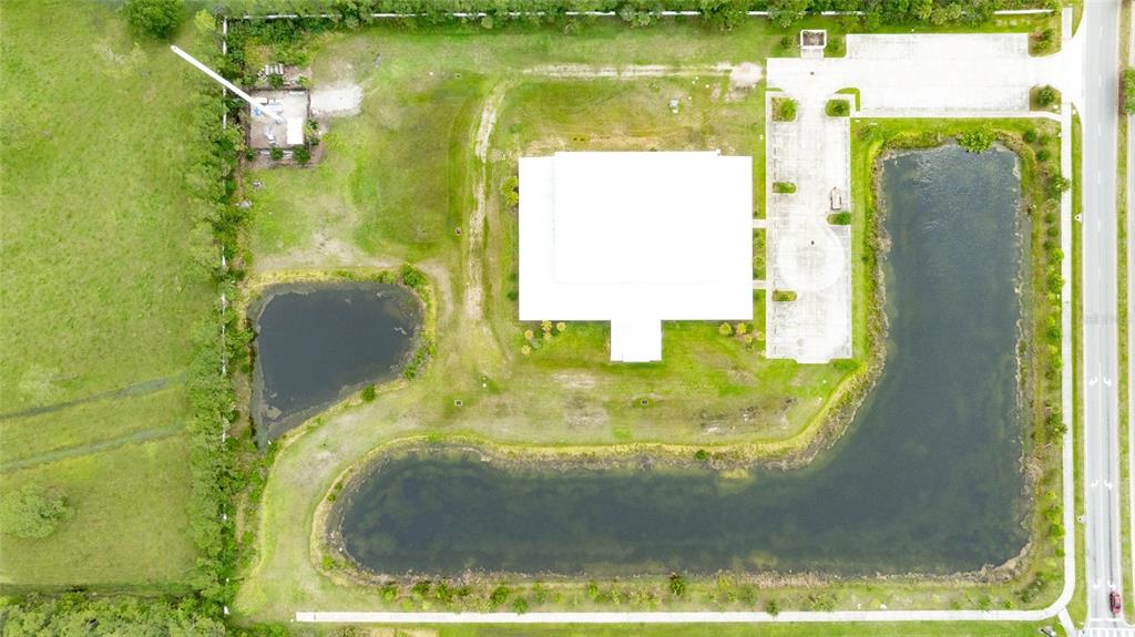 An aerial view shows a building with a white roof surrounded by ponds and parking — 4015 S WILLIAMSON BOULEVARD, PORT ORANGE, FL