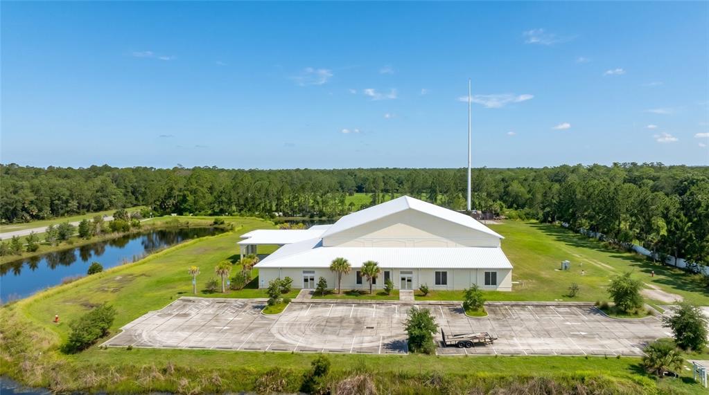An aerial view shows a large white building with a parking lot and a pond — 4015 S WILLIAMSON BOULEVARD, PORT ORANGE, FL