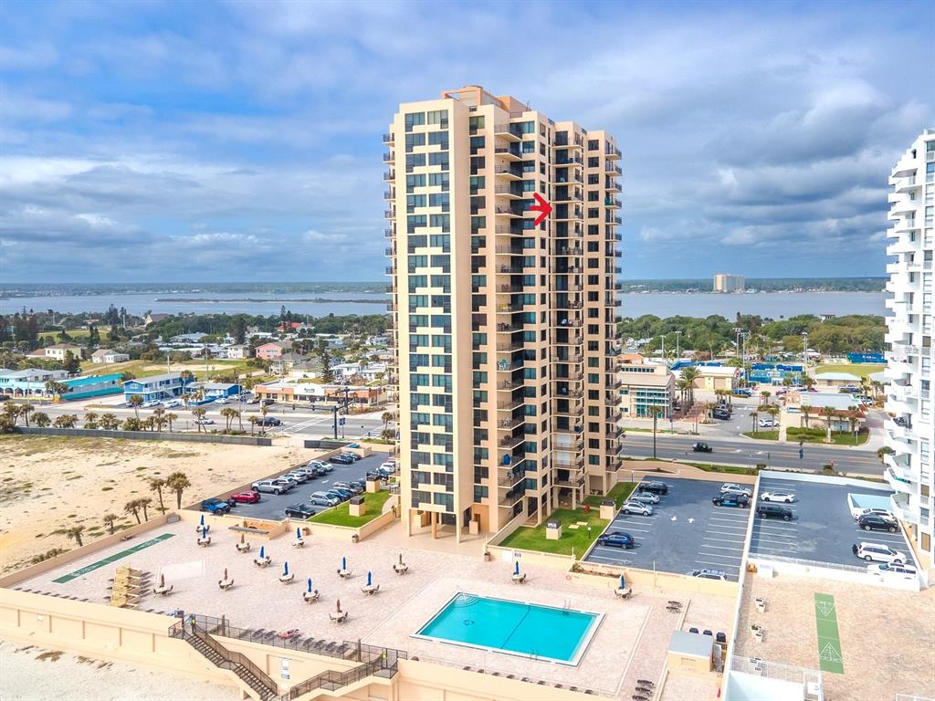 An aerial view shows a tall tan residential building with balconies and a swimming pool — 3051 S. ATLANTIC AVENUE UNIT 1805, DAYTONA BEACH SHORES, FL
