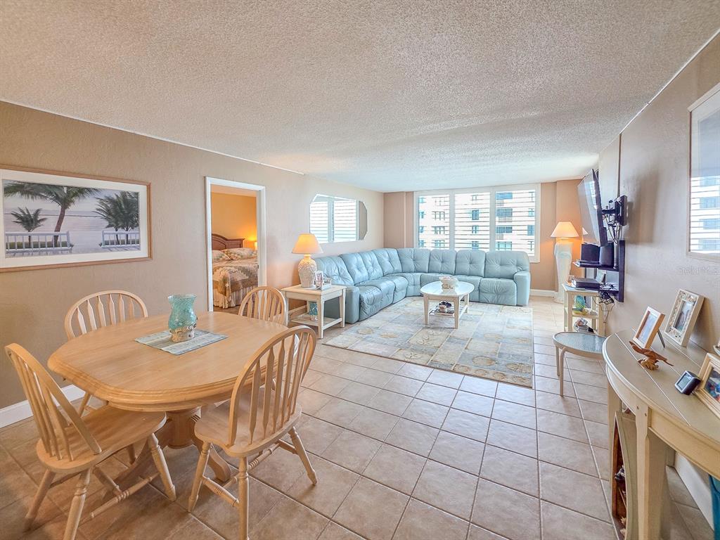 An open-concept living and dining area features tile flooring, a light blue sectional, and furniture — 3051 S. ATLANTIC AVENUE UNIT 1805, DAYTONA BEACH SHORES, FL