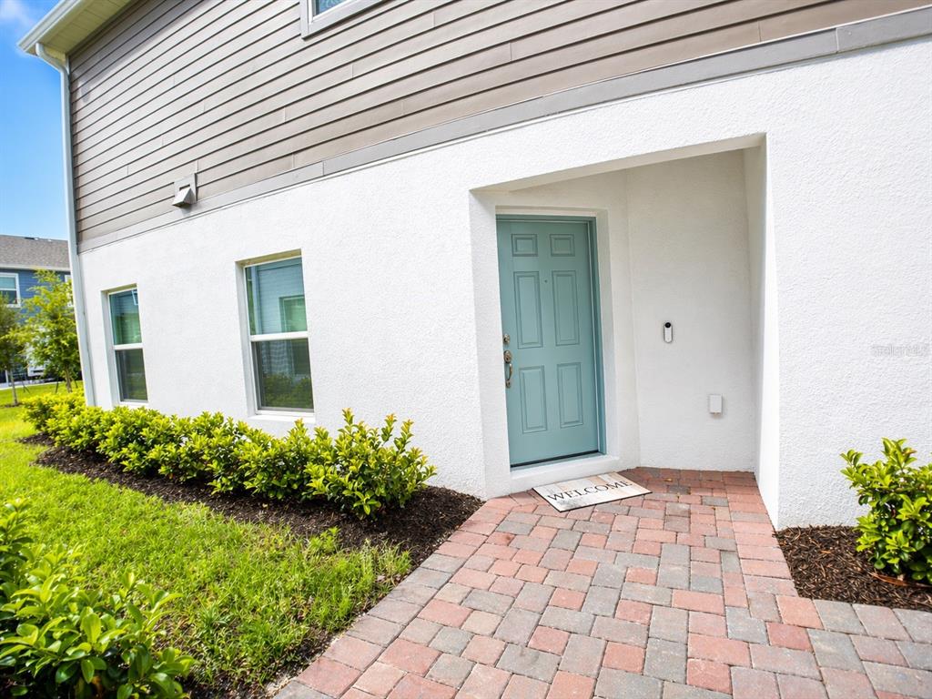 A light blue front door sits in a recessed entryway with a brick paver walkway — 5076 RAIN SHADOW DRIVE, ST CLOUD, FL