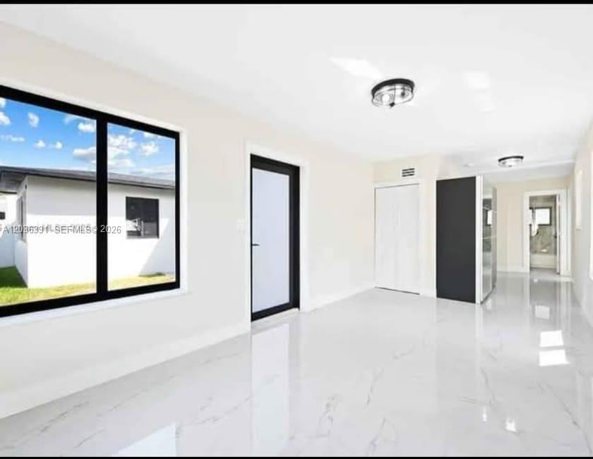 A bright room with white marble-style flooring, a black-framed door, and a large window — 721 SW 5th Ct # 0, Hallandale Beach FL 33009, HALLANDALE BEACH, FL