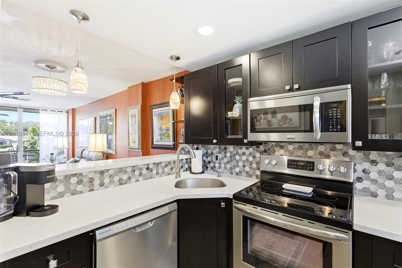 A kitchen features dark cabinets, stainless steel appliances, a hexagonal tile backsplash, and white countertops — 111 Royal Park Dr # 2E, Oakland Park FL 33309, OAKLAND PARK, FL