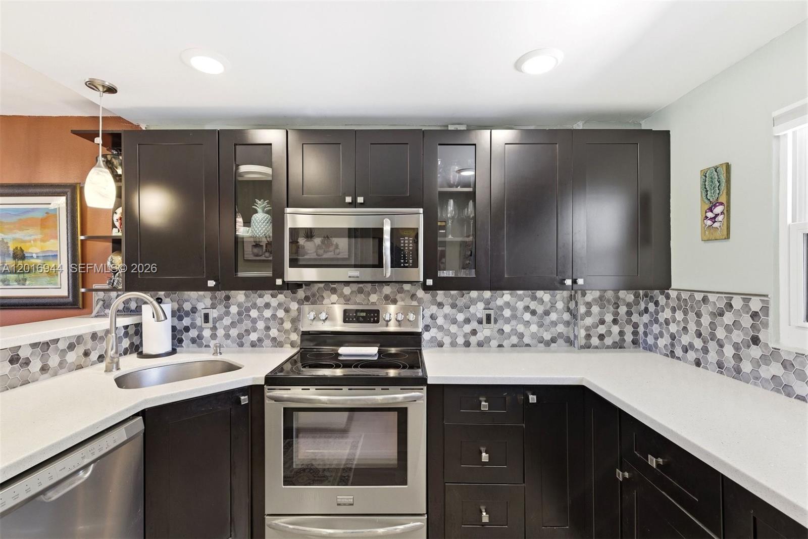 A kitchen features dark wood cabinets, stainless steel appliances, white countertops, and a hexagonal backsplash — 111 Royal Park Dr # 2E, Oakland Park FL 33309, OAKLAND PARK, FL