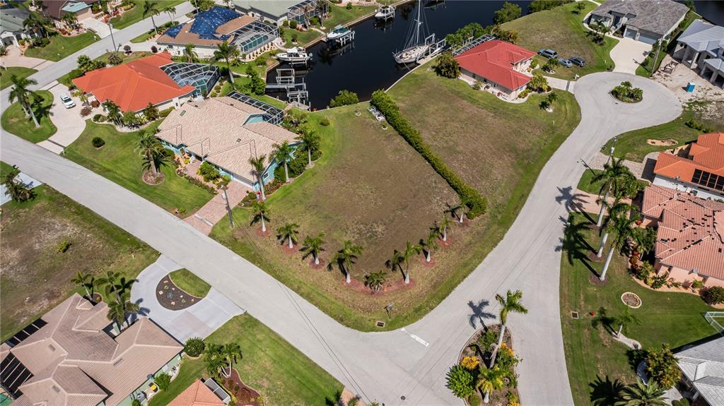 An aerial view shows a vacant residential lot surrounded by houses and a canal — 1423 GREBE COURT, PUNTA GORDA, FL