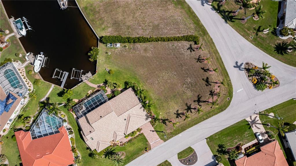 An aerial view shows a vacant waterfront lot situated between two houses and a canal — 1423 GREBE COURT, PUNTA GORDA, FL
