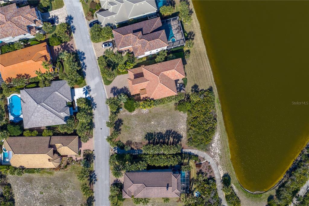 An aerial view shows a vacant residential lot situated between two houses near a lake — 29 SANDPIPER LANE, PALM COAST, FL