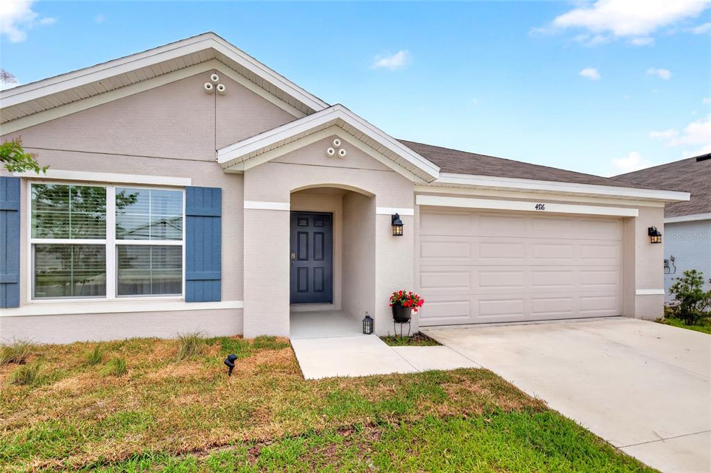 A single-story house with a beige stucco exterior, blue shutters, and a two-car garage — 4716 SW 85TH PLACE, OCALA, FL