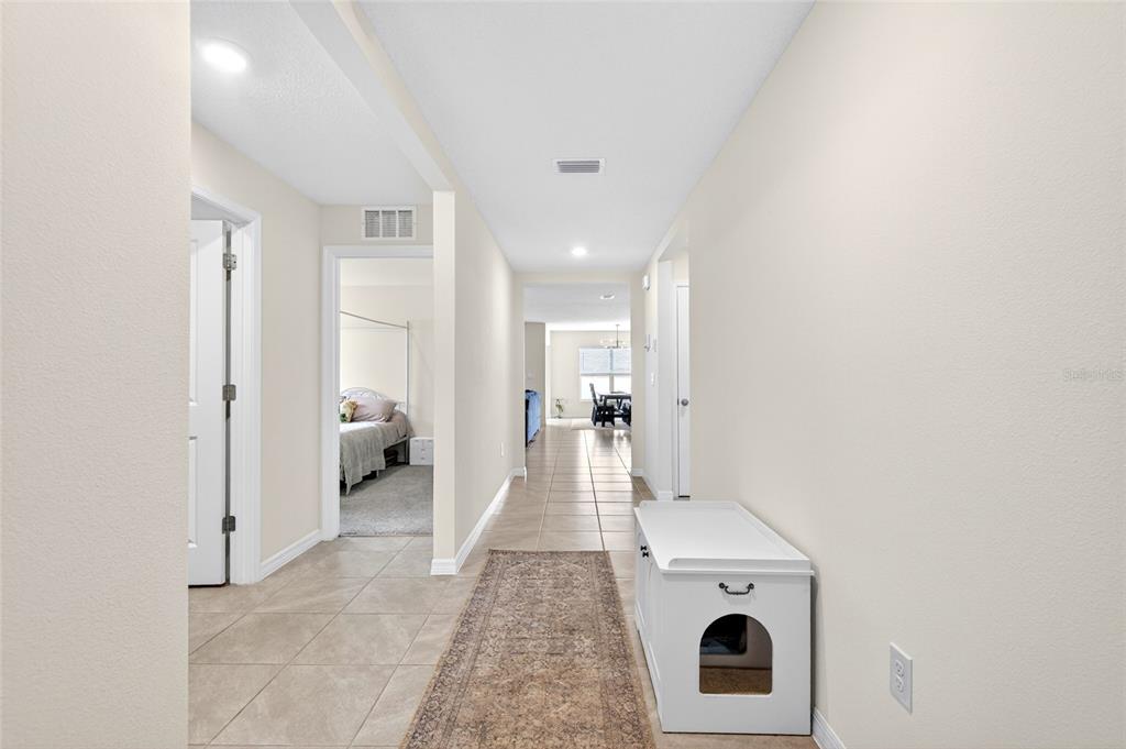 A tiled hallway leads past a bedroom and a white cat litter box enclosure — 4716 SW 85TH PLACE, OCALA, FL