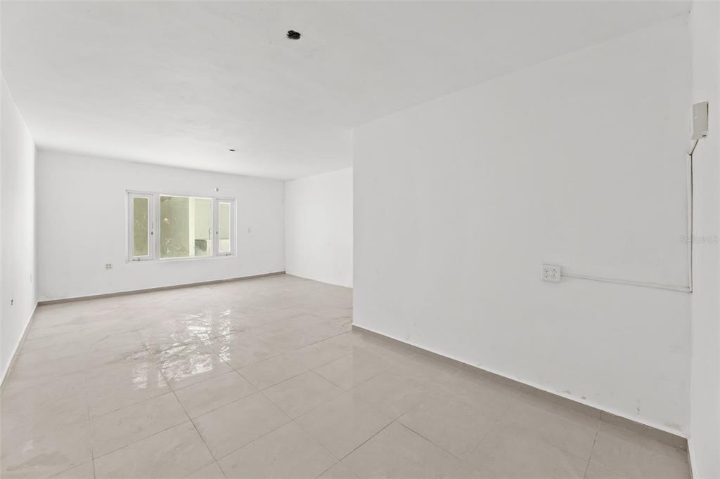 An empty room with white walls, light tile flooring, and a window on the left — 3RD STREET HERNAOS DAVILA, BAYAMON, PR