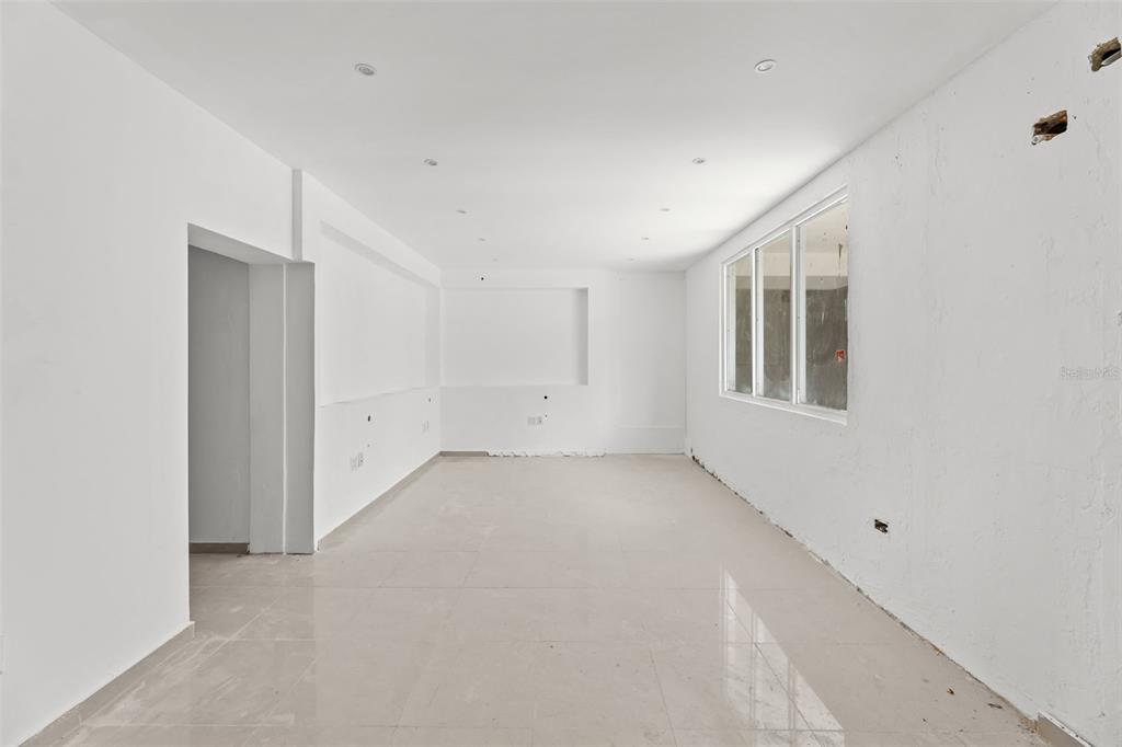 An empty, white-walled room features recessed lighting, large windows, and light-colored tiled flooring — 3RD STREET HERNAOS DAVILA, BAYAMON, PR