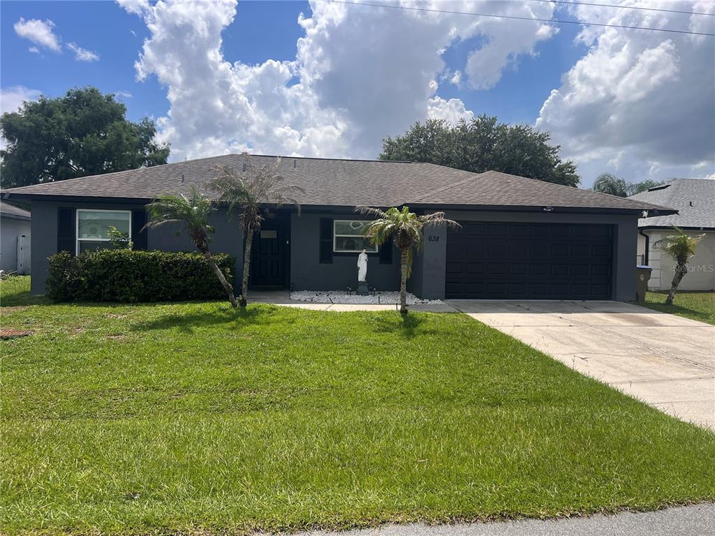 A living room features a large wall-mounted television, two navy armchairs, and a black sofa — 638 BALDWIN DRIVE, KISSIMMEE, FL