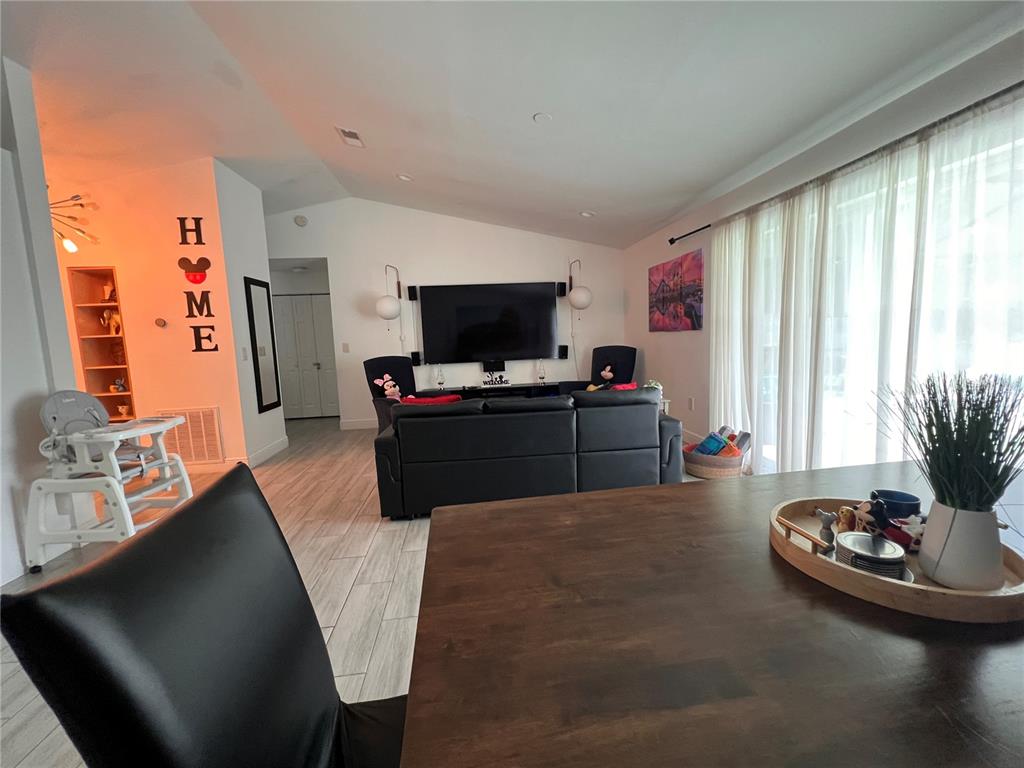 An open-concept living and dining area features a black sectional, wooden table, and tile flooring — 638 BALDWIN DRIVE, KISSIMMEE, FL