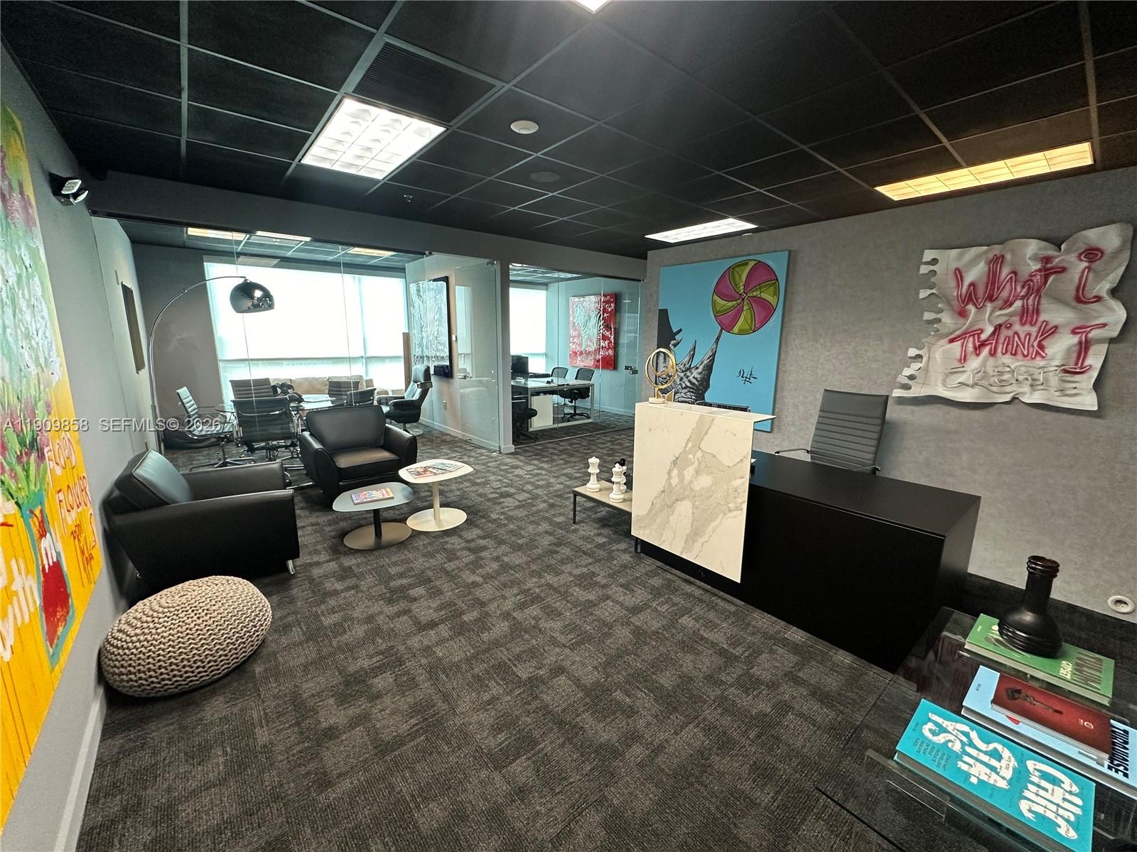 A modern office space features a black desk, lounge seating, and contemporary wall art — 175 SW 7 ST # 1101, Miami FL 33130, MIAMI, FL