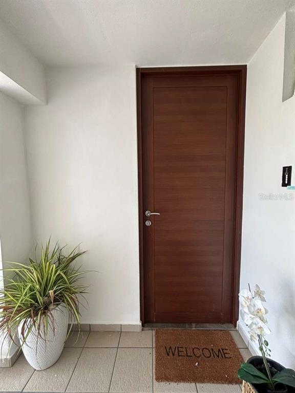A wooden door with a silver handle is centered in a white entryway with tile flooring — PH 1-A ARROYO BEACH RESORT UNIT PH1-A, ARROYO, PR