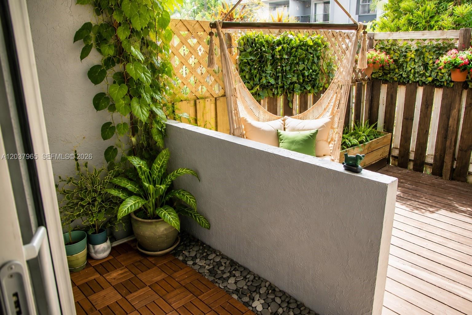 A patio features a hanging hammock chair, potted plants, wood decking, and a privacy wall — 4600 SW 67th Ave # 127, Miami FL 33155, MIAMI, FL