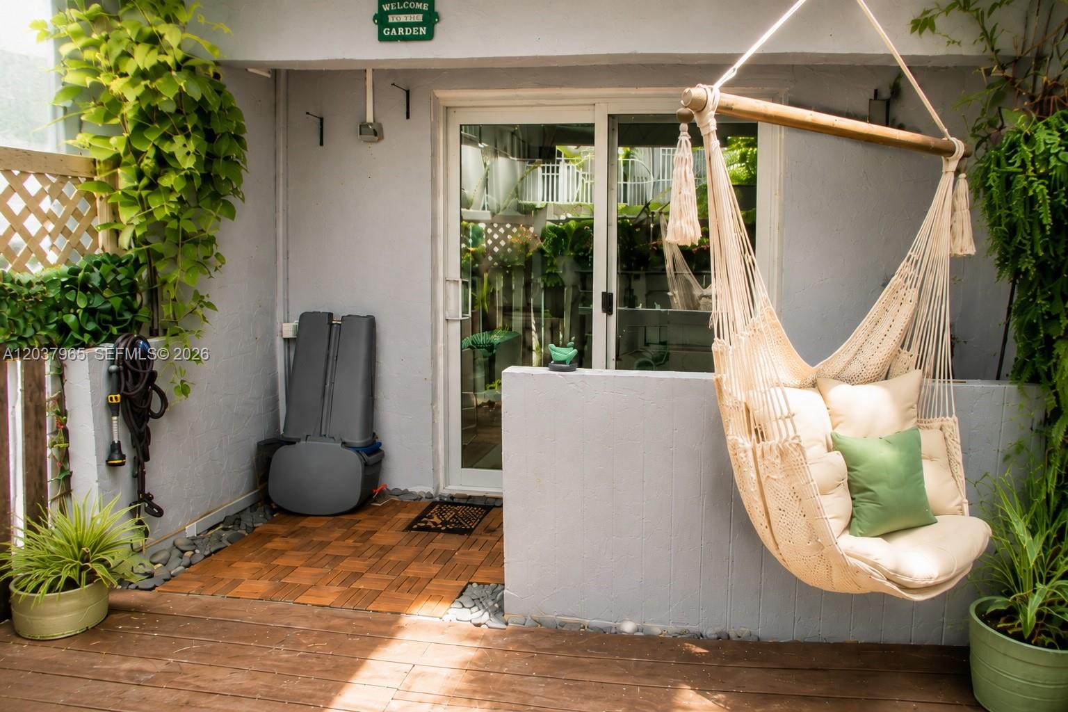A patio features a hanging chair, wood decking, a sliding glass door, and potted plants — 4600 SW 67th Ave # 127, Miami FL 33155, MIAMI, FL