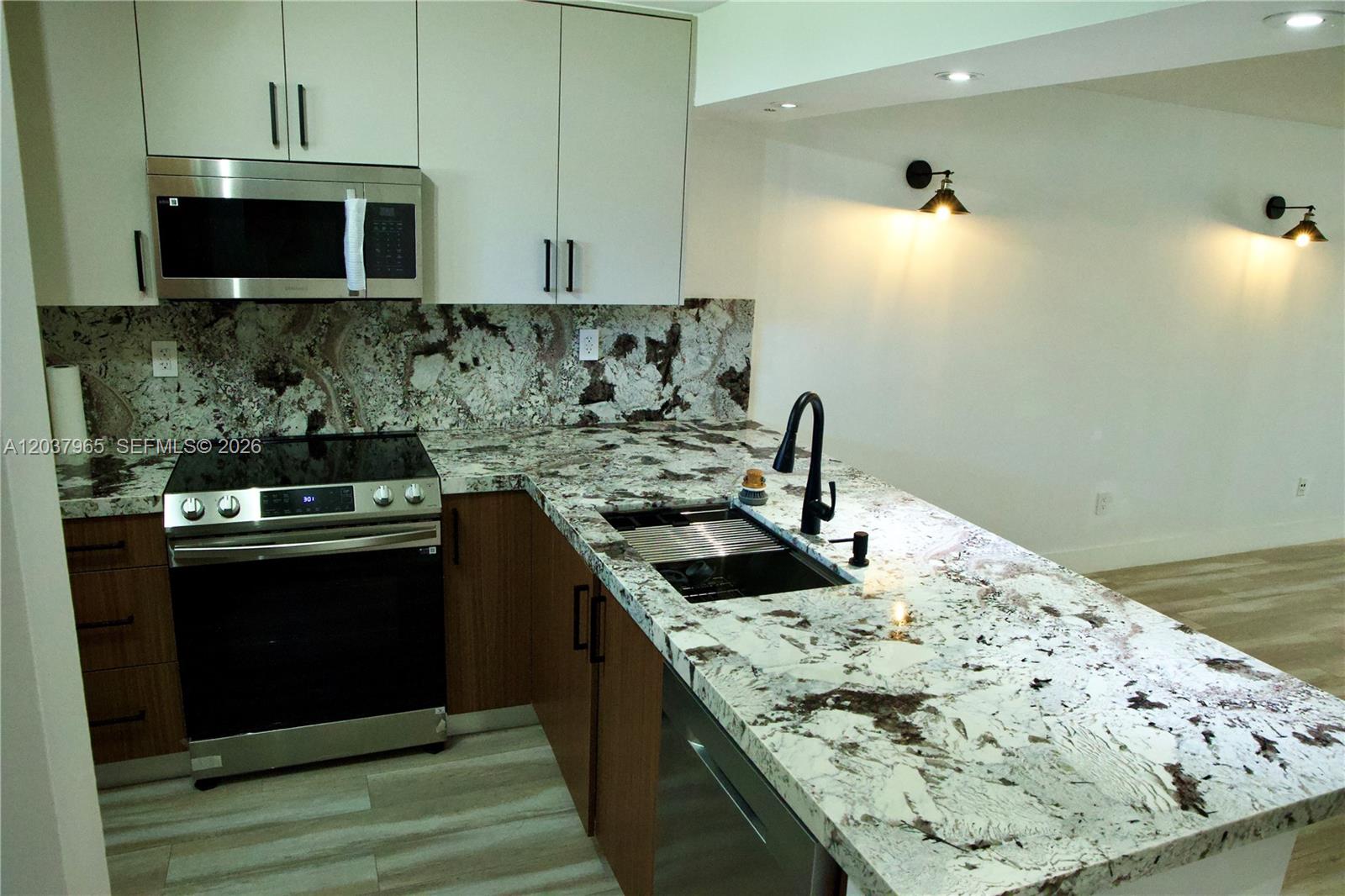 A kitchen features white upper cabinets, wood lower cabinets, and a patterned granite countertop — 4600 SW 67th Ave # 127, Miami FL 33155, MIAMI, FL