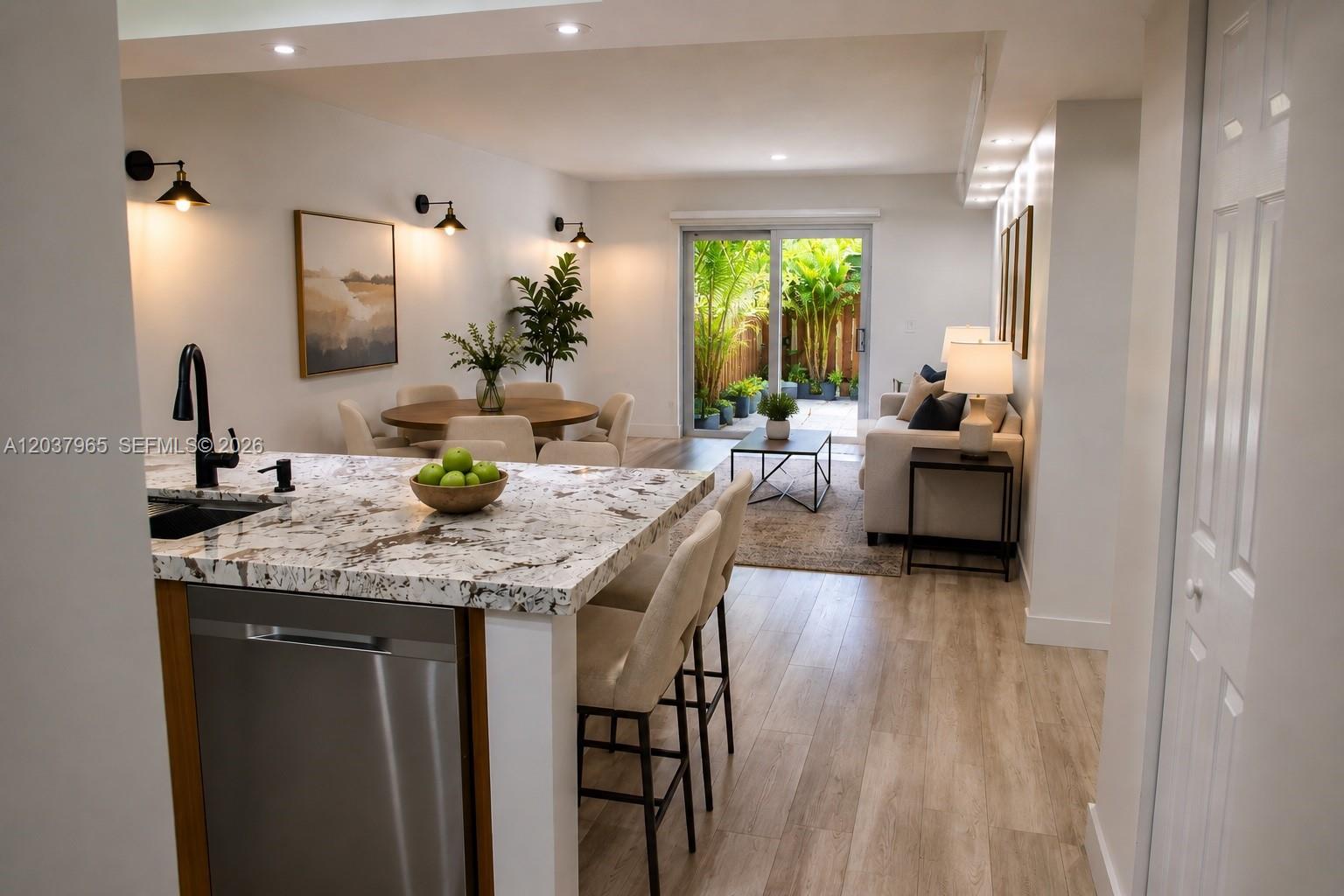 An open-concept kitchen, dining area, and living room with light wood floors and sliding doors — 4600 SW 67th Ave # 127, Miami FL 33155, MIAMI, FL