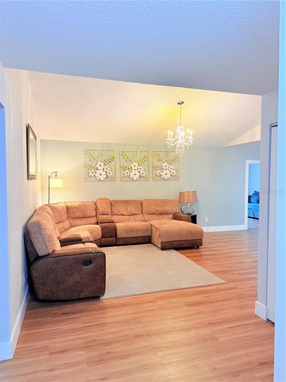 A living room features a large brown sectional sofa, a light rug, and a crystal chandelier — 2130 REDLEAF DRIVE, BRANDON, FL