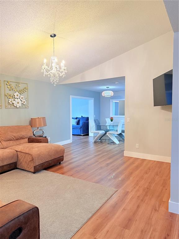 A living room with a brown sectional sofa leads into a dining area with wood floors — 2130 REDLEAF DRIVE, BRANDON, FL