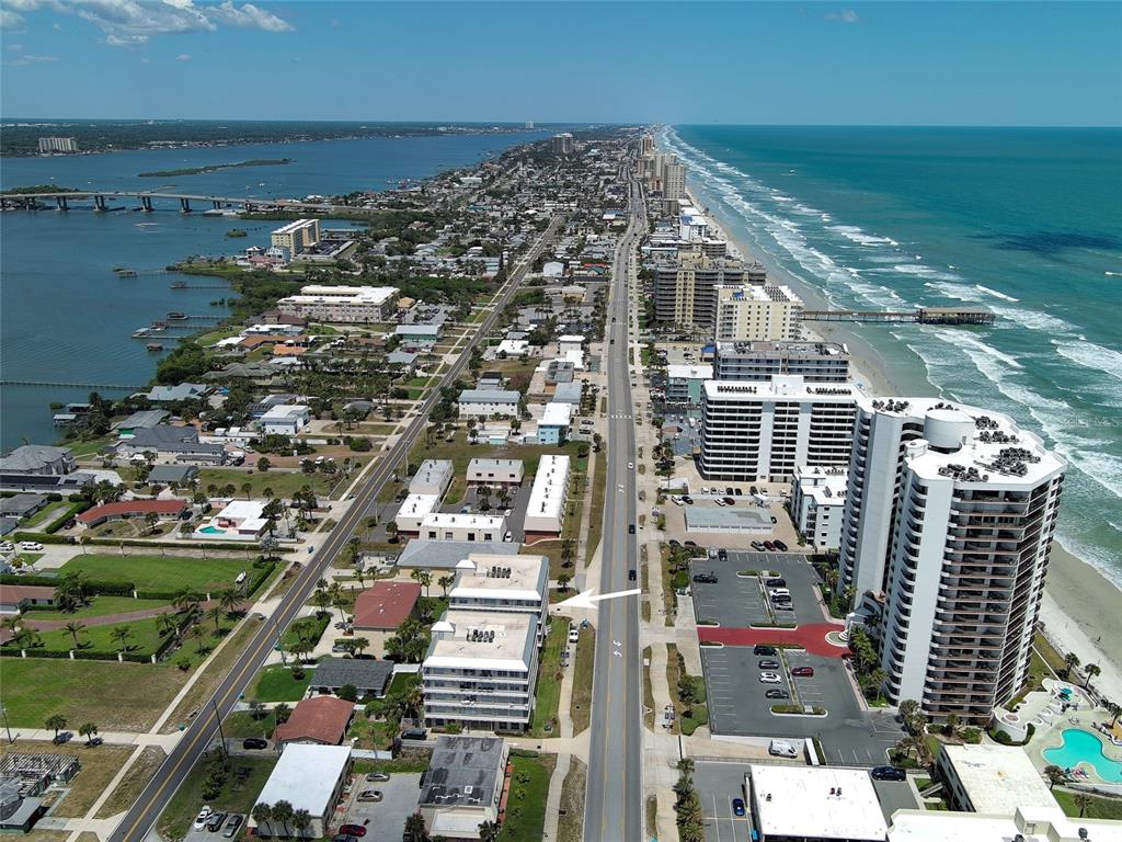 An aerial view shows a coastal town with a multi-story building highlighted by an arrow — 3756 S ATLANTIC AVENUE UNIT 201, DAYTONA BEACH, FL