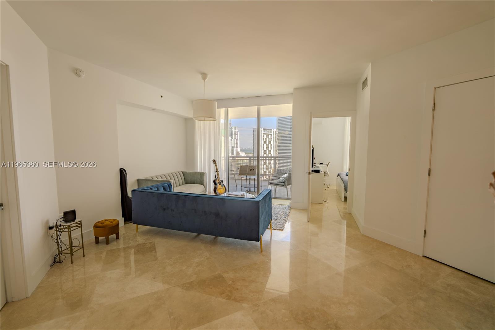 A living room features a blue velvet sofa, marble floors, and a balcony with city views — 350 S Miami Ave # 3203, Miami FL 33130, MIAMI, FL