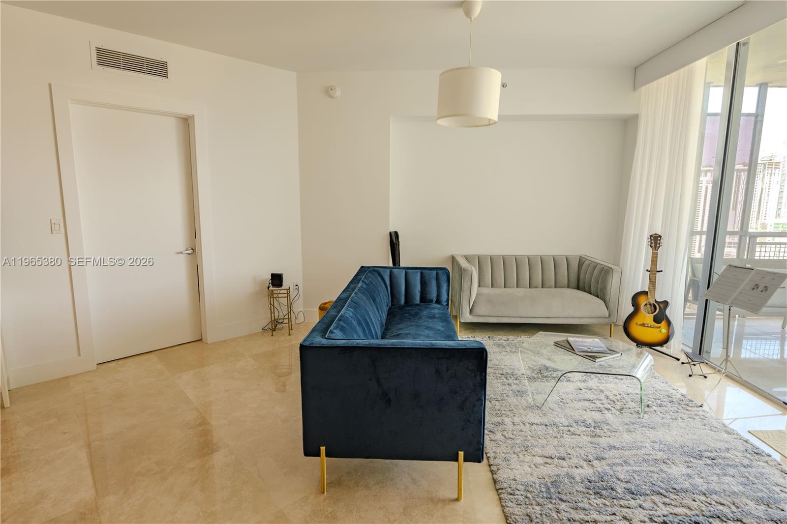 A living room features a blue velvet sofa, a grey sofa, and a glass coffee table — 350 S Miami Ave # 3203, Miami FL 33130, MIAMI, FL