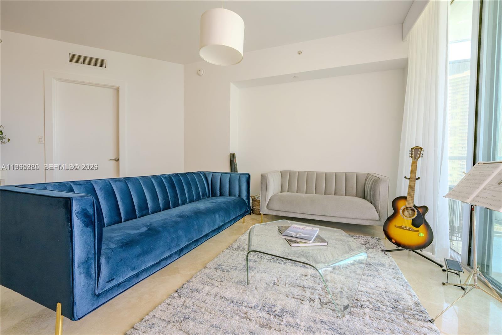 A living room features a blue velvet sofa, a grey sofa, and a glass coffee table — 350 S Miami Ave # 3203, Miami FL 33130, MIAMI, FL