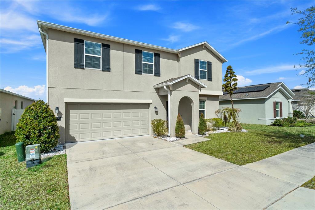 A two-story suburban house features a beige stucco exterior, a two-car garage, and shutters — 144 TAFT DRIVE, DAVENPORT, FL