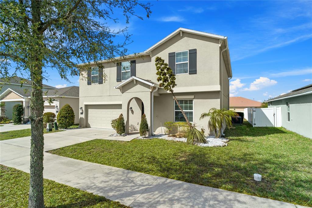 A two-story suburban house with a beige stucco exterior, a garage, and a front lawn — 144 TAFT DRIVE, DAVENPORT, FL