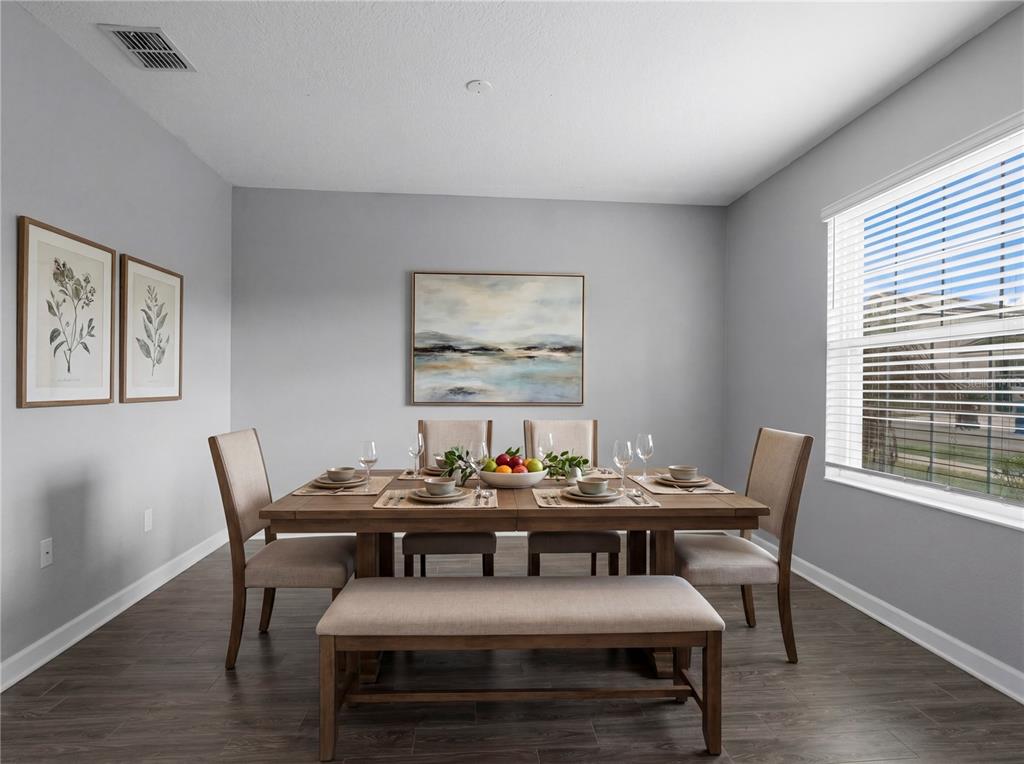 A dining room features a wooden table, chairs, a bench, and framed wall art — 144 TAFT DRIVE, DAVENPORT, FL