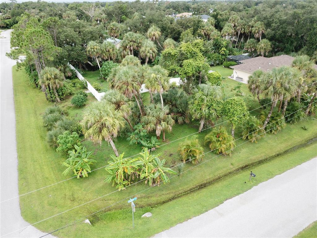 An aerial view shows a corner lot with dense tropical landscaping and palm trees — CARIBOU AVENUE, NORTH PORT, FL