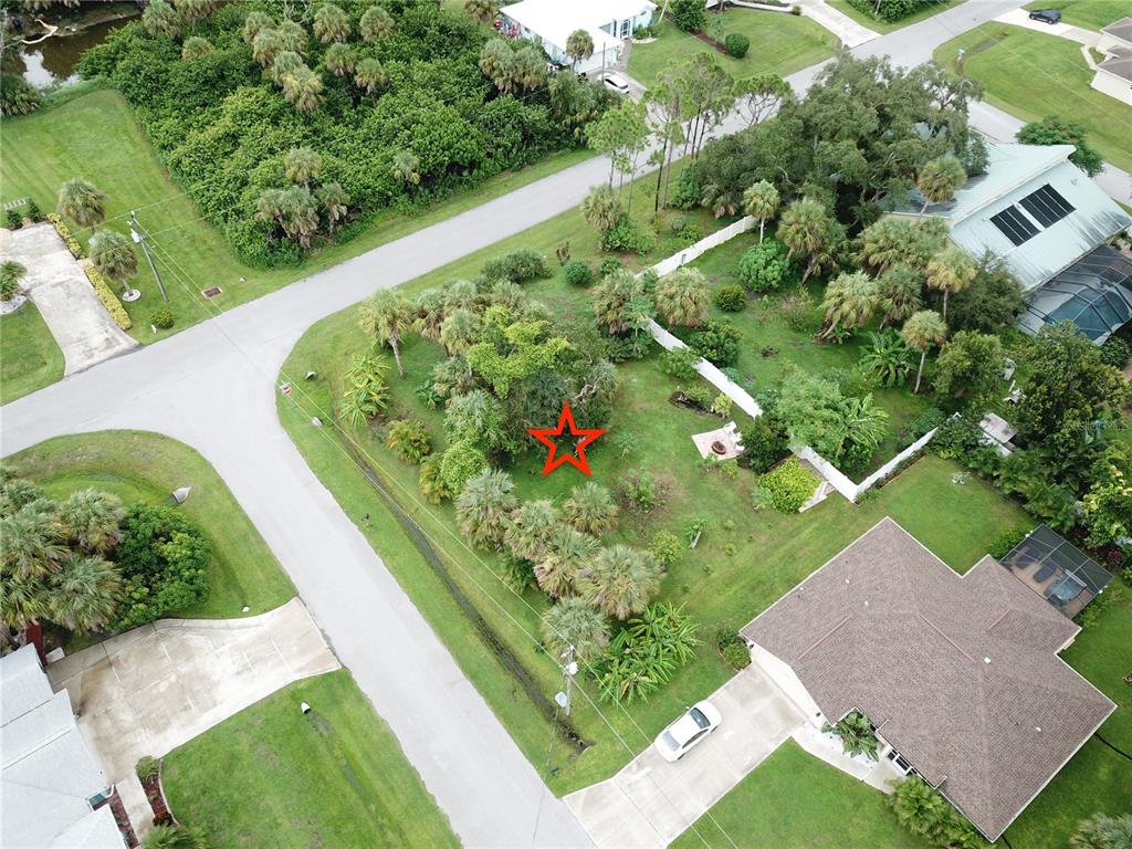 An aerial view shows a vacant, tree-filled residential lot marked with a red star — CARIBOU AVENUE, NORTH PORT, FL