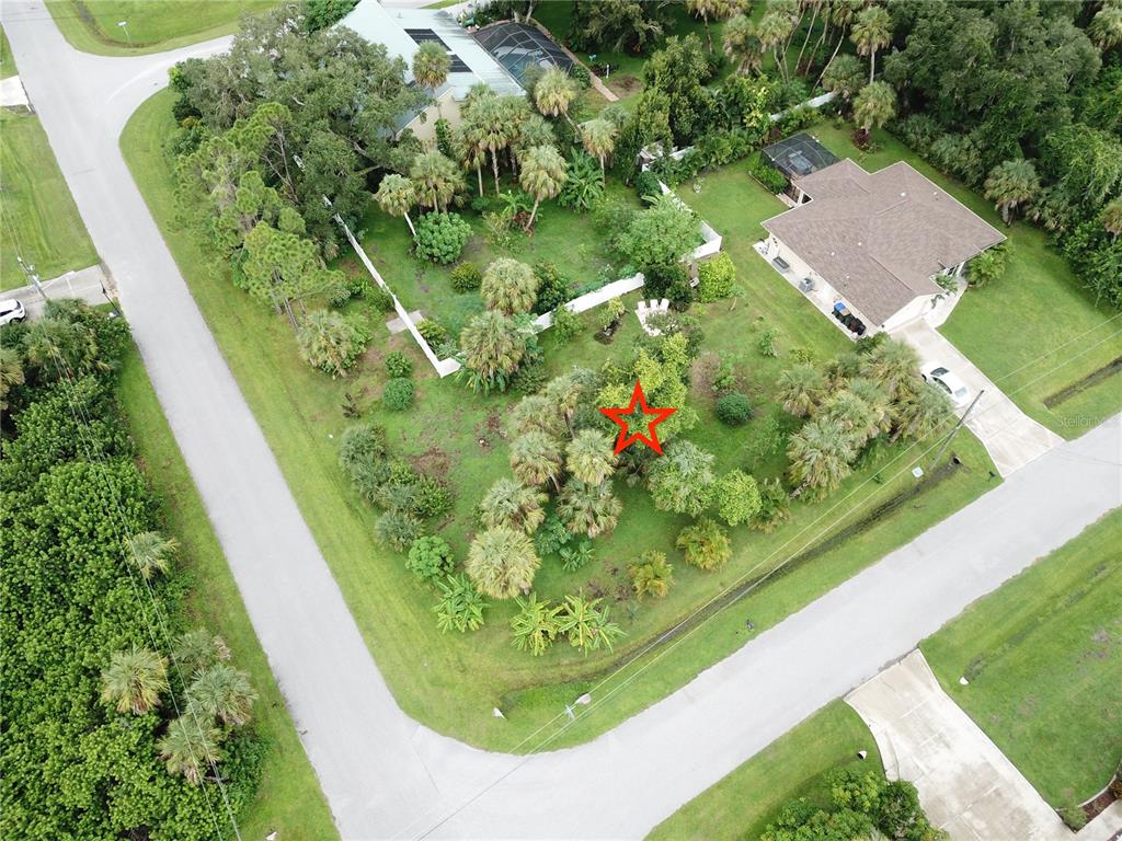 An aerial view shows a vacant, tree-filled residential lot with a red star marker — CARIBOU AVENUE, NORTH PORT, FL
