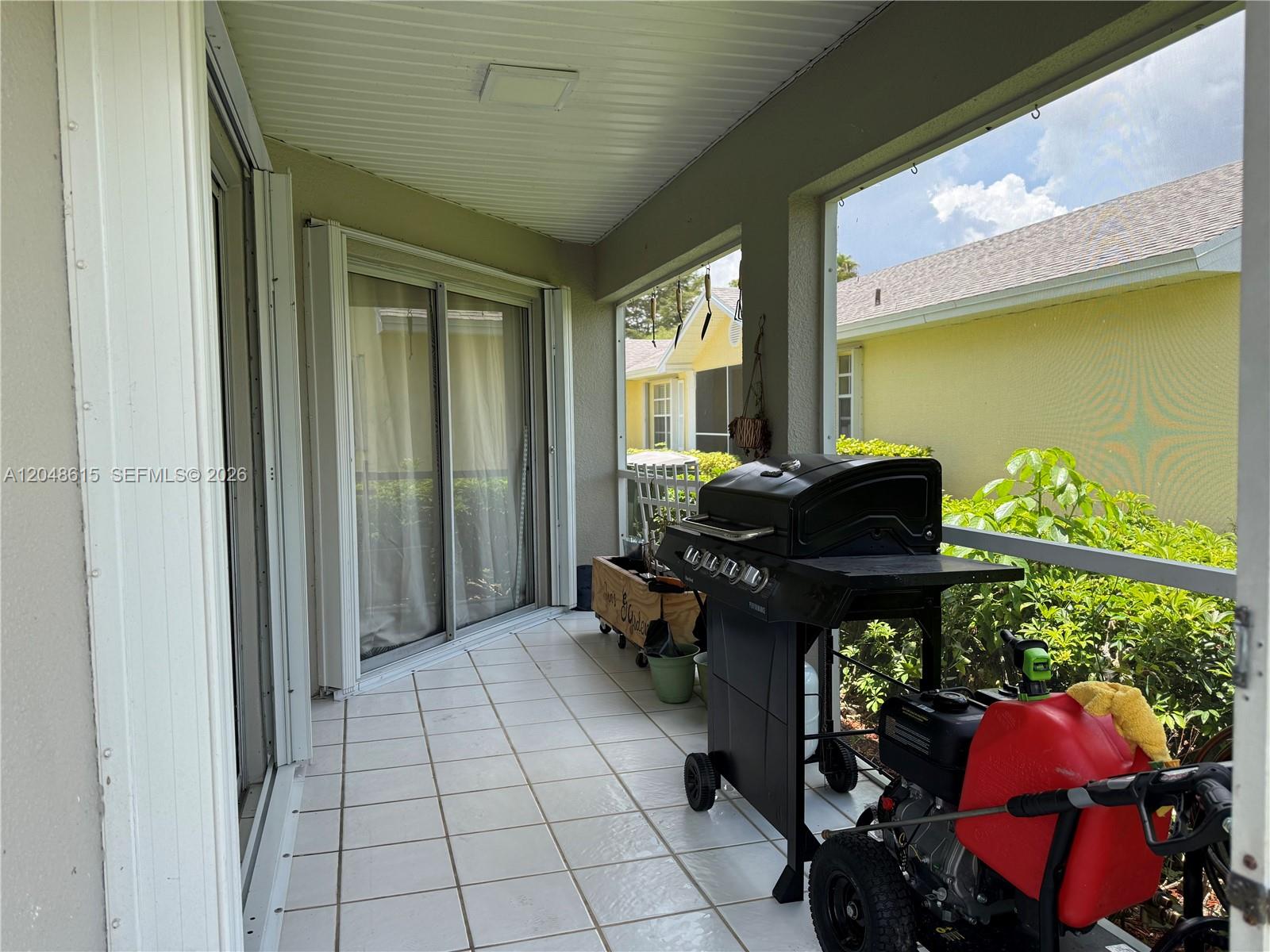 A tiled, screened-in patio features a grill and a pressure washer near sliding glass doors — 2225 SE 5th Pl, Homestead FL 33033, HOMESTEAD, FL