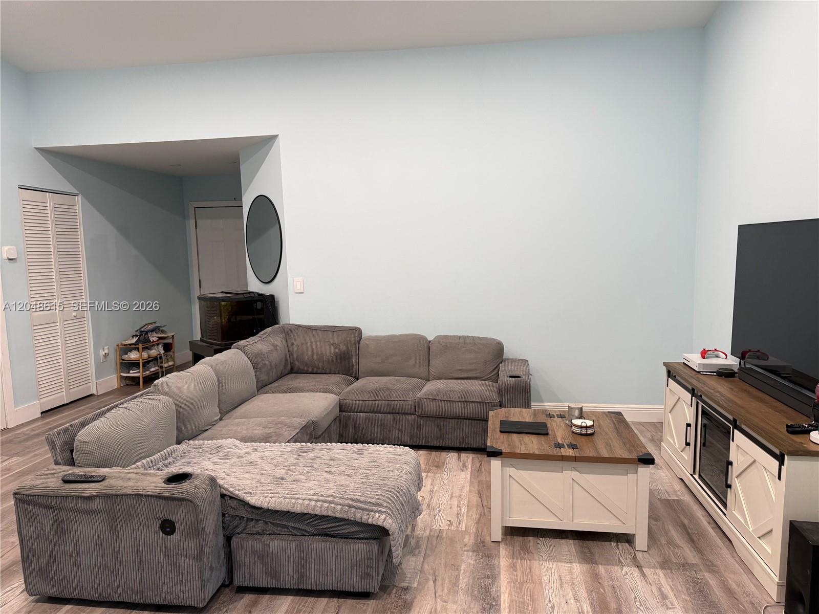 A living room features a large gray sectional sofa, a coffee table, and a television console — 2225 SE 5th Pl, Homestead FL 33033, HOMESTEAD, FL