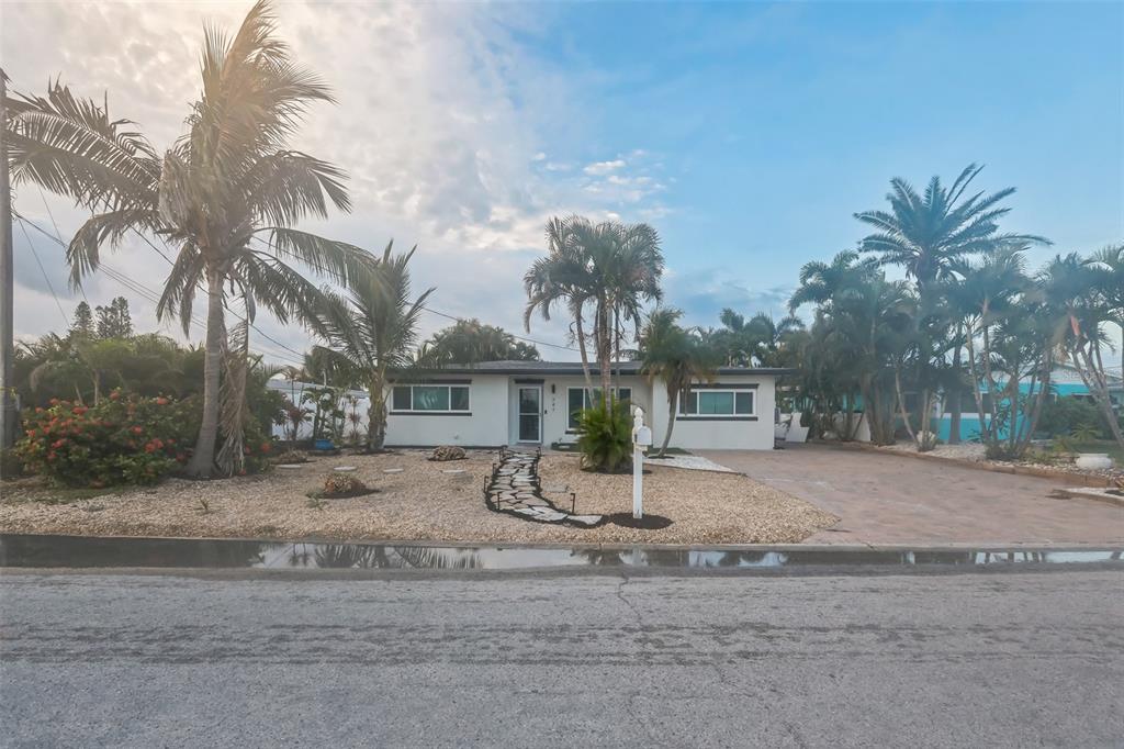 A single-story white house with a stone walkway and palm trees in the front yard — 747 PRUITT DRIVE, MADEIRA BEACH, FL