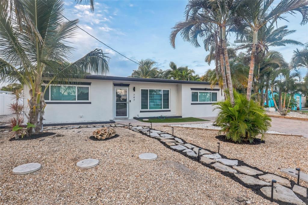 A single-story white house with dark trim, palm trees, and a stone walkway — 747 PRUITT DRIVE, MADEIRA BEACH, FL