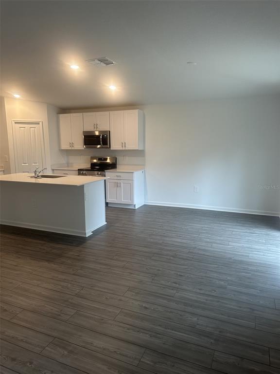 A kitchen with white cabinets, stainless steel appliances, and a central island on wood flooring — 13110 SW 89 STREET, OCALA, FL