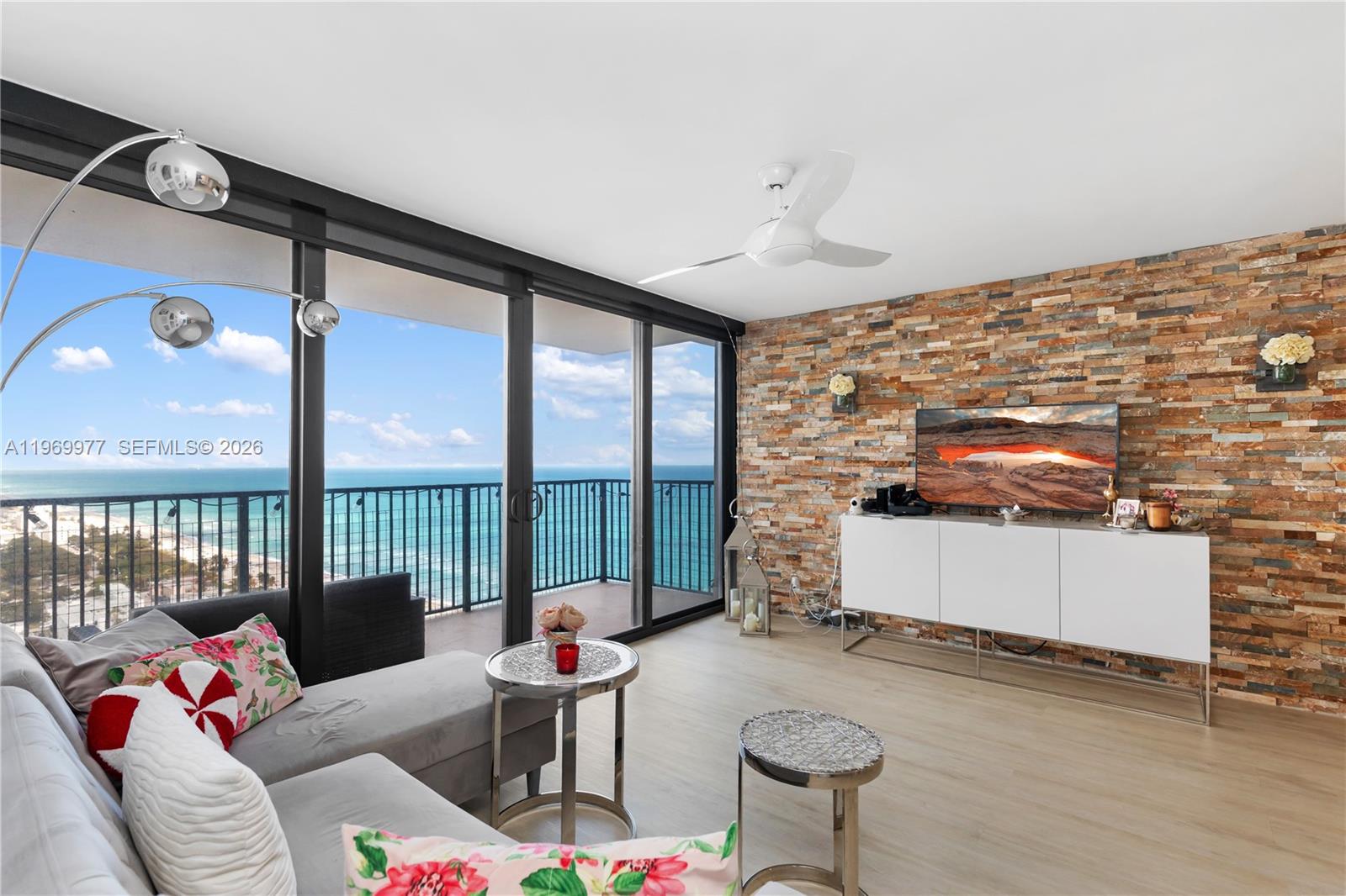 A living room features a stone accent wall, white media console, and floor-to-ceiling ocean views — 2101 S Ocean Dr # 2804, Hollywood FL 33019, HOLLYWOOD, FL