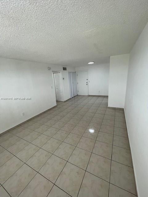 An empty room with white walls, a textured ceiling, and light-colored tiled flooring — 606 W 81st St # 408, Hialeah FL 33014, HIALEAH, FL