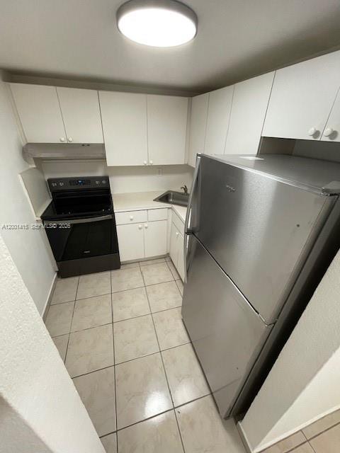 A galley-style kitchen features white cabinets, stainless steel appliances, and light-colored tile flooring — 606 W 81st St # 408, Hialeah FL 33014, HIALEAH, FL