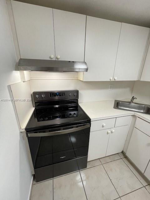 A kitchen features white cabinets, a stainless steel range hood, and a black electric stove — 606 W 81st St # 408, Hialeah FL 33014, HIALEAH, FL